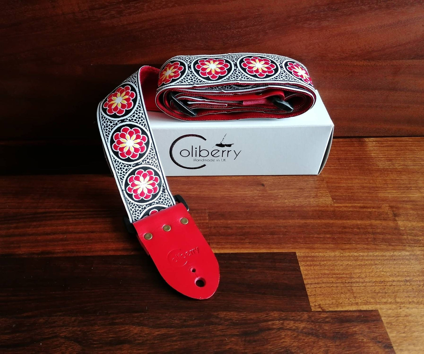 Handmade guitar strap. Red and Black embroidered flower Ribbon with Red Seatbelt backing and Red Leather ends.