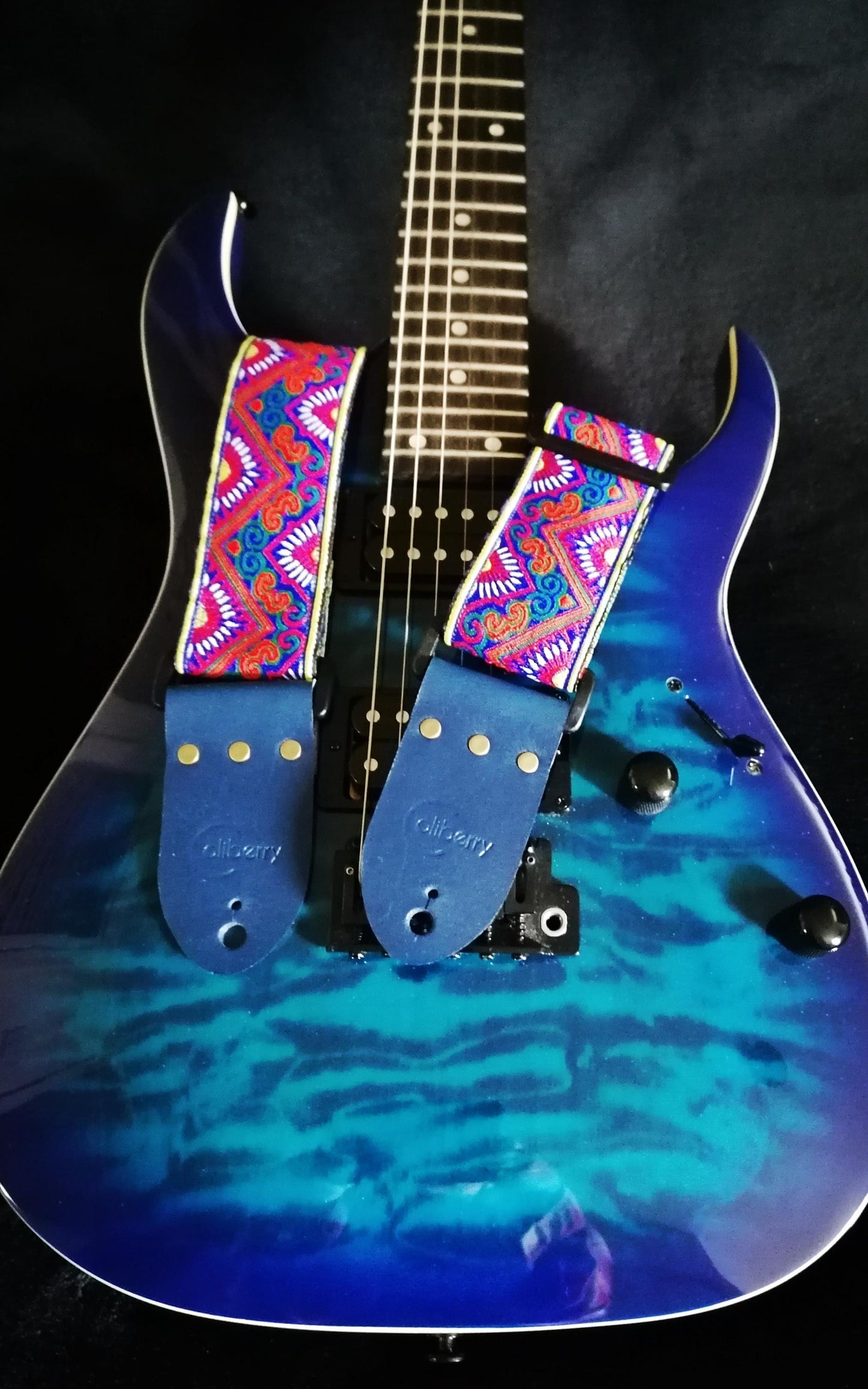 Handmade guitar strap - 'BlueTribal Horn' Blue, Red, Yellow Jaquard Ribbon with Blue Seatbelt backing and Antique Blue Real Leather ends.