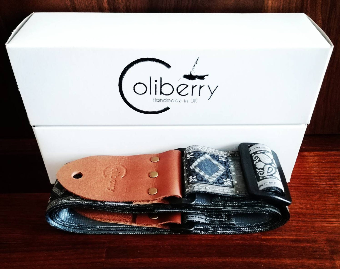 Handmade guitar strap. Grey with geometric design and  seat belt backing. Finished with Montana hazelnut leather ends