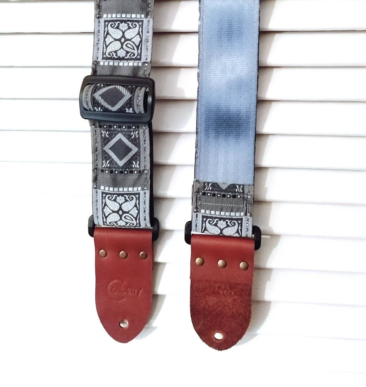 Handmade guitar strap. Grey with geometric design and  seat belt backing. Finished with Montana hazelnut leather ends